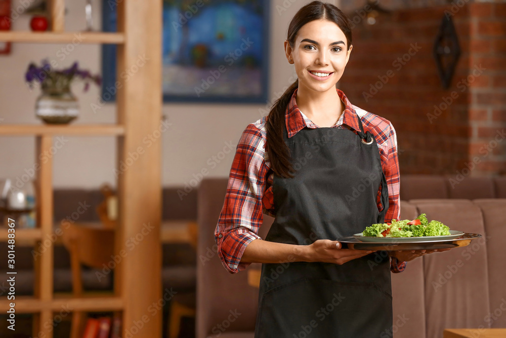 Young waitress with salad in restaurant