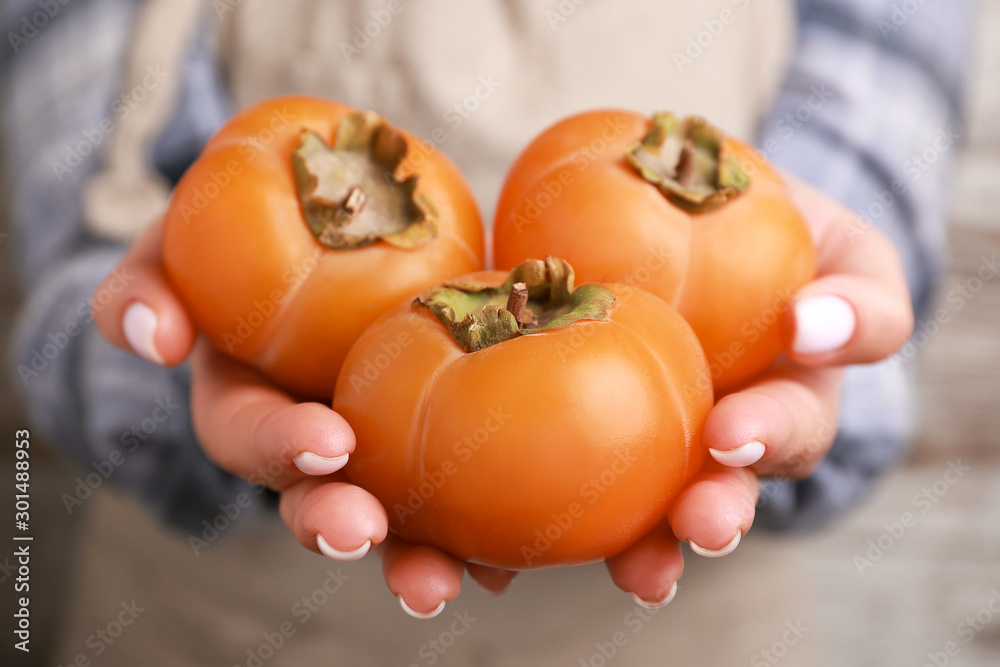 Woman holding ripe persimmons, closeup