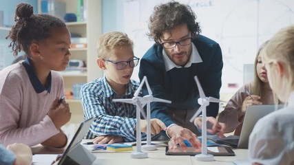 Poster - elementary school classroom: enthusiastic teacher holding tablet computer explains to a brilliant yo