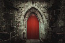 Scary Pointy Red Wooden Door In An Old And Wet Stone Wall Building With Cross, Skull And Bones At Both Sides. Concept Mystery, Death And Danger.