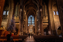LIVERPOOL, ENGLAND, DECEMBER 27, 2018: People Walking Along The Entrance Hall Of The Church Of England Anglican Cathedral Of The Diocese Of Liverpool With A Christmas Tree Aside During Holidays.