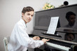 Young man enjoying playing an old nostalgic melody as he sits at an upright piano reading an old music score