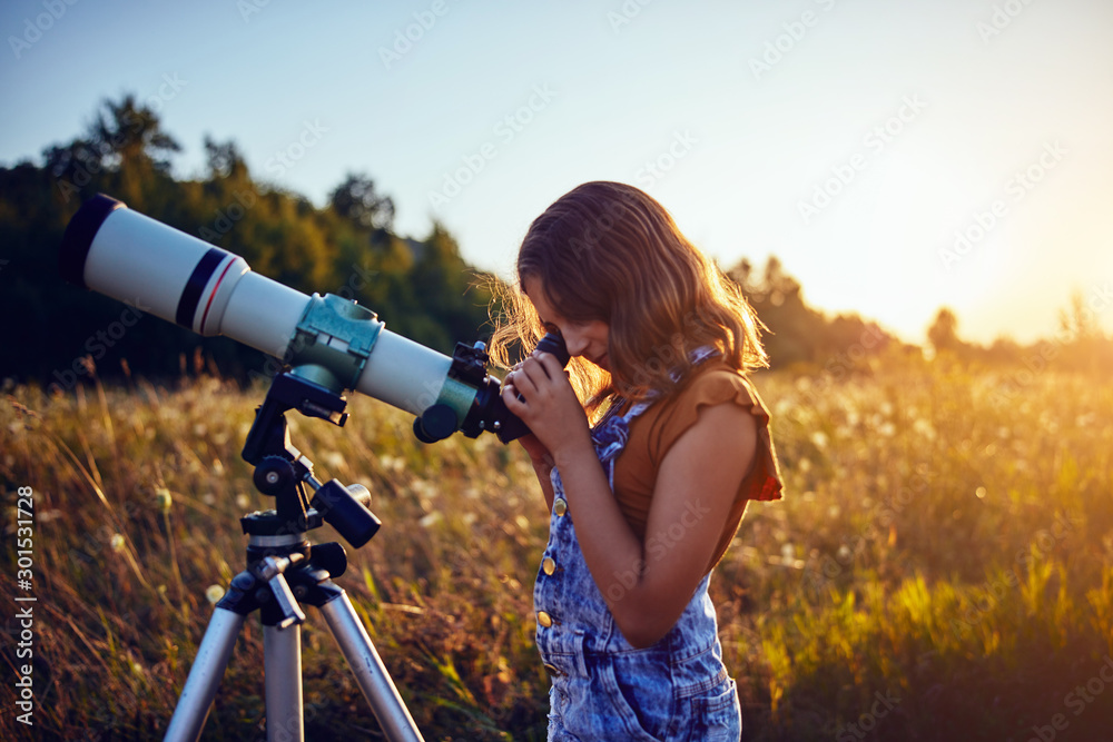 Little girl using telescope in nature to explore the universe. - obrazy, fototapety, plakaty 
