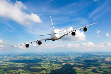 White passenger plane in flight. The plane flies against a background of a endless horizon. Aircraft left inclination / front view.