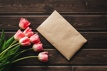 Wall Mural - pink flowers tulips with a paper postal envelope on a wooden rustic table
