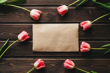Wall Mural - pink flowers tulips with a paper postal envelope on a wooden table