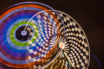 Two rides in motion in amusement park, night illumination. Long exposure.