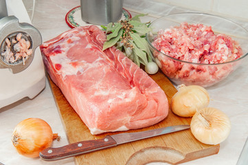 A piece of meat is ready for chopping. Cook makes minced fresh meat in a meat grinder