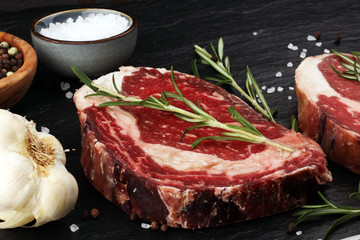 Wall Mural - Raw fresh meat Ribeye Steak, seasoning and meat fork on rustic background