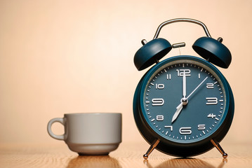 Wall Mural - alarm clock with cup of coffee on a table