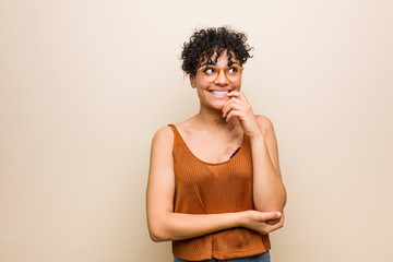 Wall Mural - Young african american woman with skin birth mark relaxed thinking about something looking at a copy space.