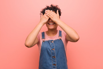 Wall Mural - Young mixed african american teenager woman covers eyes with hands, smiles broadly waiting for a surprise.