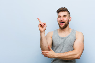 Wall Mural - Young handsome fitness man smiling cheerfully pointing with forefinger away.