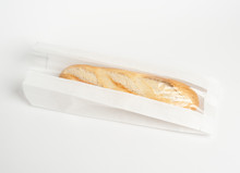 Loaf Of Fresh Baked Artisan Baguette Bread In Market Paper Bag Over White Background. Top View, Copy Space. Packaging Concept