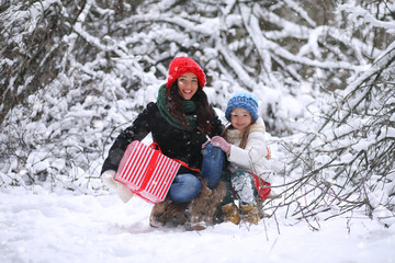 A winter fairy tale in the forest. A girl on a sled with gifts on the eve of the new year in the park. Two sisters walk in a New Year's park and ride a sled with gifts.