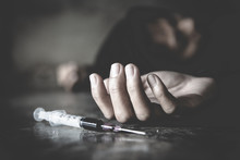Woman Hand Of A Drug Addict And A Syringe With Narcotic Syringe Lying On The Floor, Overdose, Drug Concept.