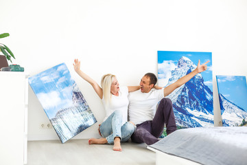 Wall Mural - young couple hangs a large photo canvas at home