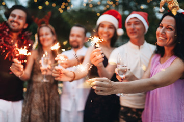 Wall Mural - Group of friends celebrating Christmas with sparkles and champagne