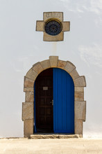 Stone Arch Church Doorway With Cross Shape Window Above And Blue Wood Door On White Wall