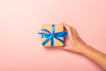 Female hand takes a gift on a pink background with confetti. Gift concept for a loved one, holiday, christmas. Flat lay, top view