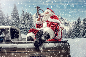 Wall Mural - Bearded in red clothes sits on the back of a white truck.Santa distributes gifts for children.Landscape of mountains and winter forest covered with snow and frost.Christmas time.Copy space.Snowflakes 