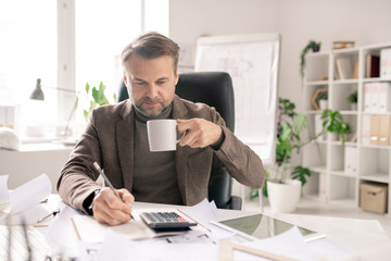 Poster - Serious mature accountant with pen and cup of coffee making calculations