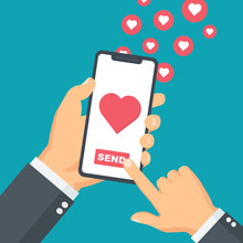 Sending Love Message Concept. Hand Holding Phone With Icon Of The Heart, Send Button On The Screen. Finger Pointing At Touch Screen. 