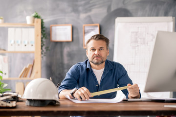 Aufkleber - Confident engineer holding measuring tape over blueprint while sitting by table