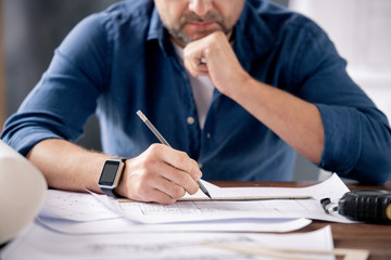 Poster - Hands of modern engineer holding pencil over ruler and sketch on blueprint