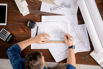 Poster - Overview of contemporary engineer sitting by table and correcting sketches
