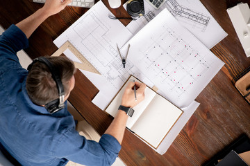 Poster - Top view of professional engineer with notebook and pencil making working notes
