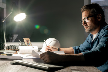 Poster - Serious architect working over new project in office late in the evening