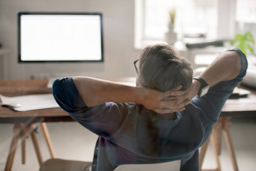 Poster - Back view of relaxed businessman with his hands behind head sitting by desk