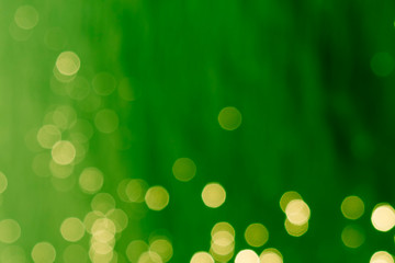 abstract spots of glowing gloden yellow light on a blurred green background