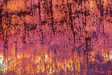 Texture of iron metal painted multicolored red yellow peeling paint of old battered scratched cracked ancient rusty metal sheet wall with corrosion. The background. Paint flows down iron.