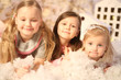 © Дмитрий Ильченко - three girls hug and smile in the New Year decorations with artificial snow and small cardboard houses