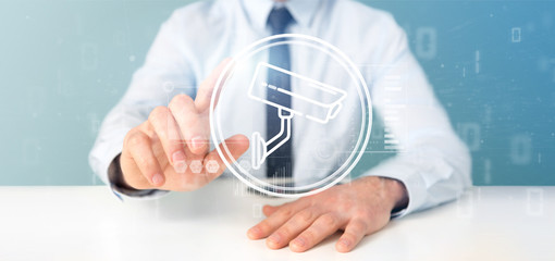 Poster - Businessman holding Security camera system icon and statistics data - 3d rendering