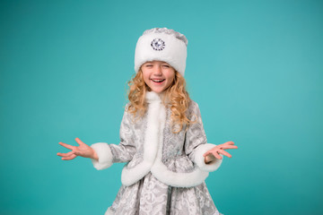 little blonde girl smiling in snow maiden costume isolate on blue background, baby catches snowflakes