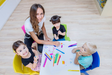 Wall Mural - Nursery teacher and students drawing with crayons