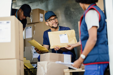 Wall Mural - Manual workers cooperating while sorting packages in a delivery van.