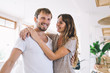 © BullRun - Half length portrait of cheerful bearded Caucasian hipster guy smiling at camera and enjoying joyful mood with lovely girlfriend hugging him, happy young marriage with amour feelings indoors