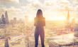 © IRStone - Young woman looking over the City of London at sunset. Beautiful city background in gentle light. Future, freedom, business success and new opportunity concept