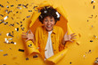 Ecstatic curly woman excited about many sales started at shopping mall, fascinated by awesome news, spreads palms and smiles toothy, wears stylish clothing, stands in hole of paper background