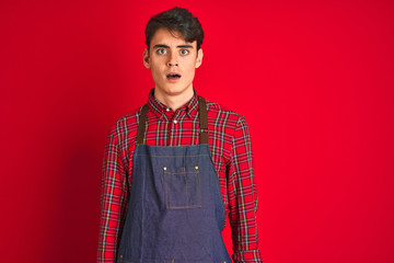 Wall Mural - Teenager boy wearing employee apron over isolated background afraid and shocked with surprise expression, fear and excited face.