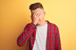 © Krakenimages.com - Young handsome man wearing casual shirt standing over isolated yellow background with sad expression covering face with hands while crying. Depression concept.