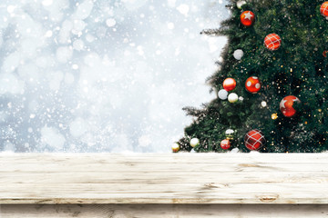 Wall Mural - top of empty wood table with beautiful christmas tree and snowfall backdrop. ready for your product 