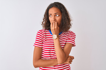 Poster - Young brazilian woman wearing red striped t-shirt standing over isolated white background looking stressed and nervous with hands on mouth biting nails. Anxiety problem.