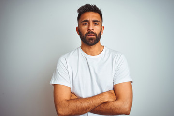 Wall Mural - Young indian man wearing t-shirt standing over isolated white background skeptic and nervous, disapproving expression on face with crossed arms. Negative person.