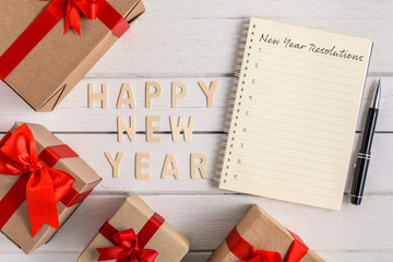 HAPPY NEW YEAR 2020 Wood and New Year's Resolutions List written on Notebook with gift box