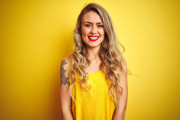 Young beautiful woman wearing t-shirt standing over yellow isolated background with a happy and cool smile on face. Lucky person.